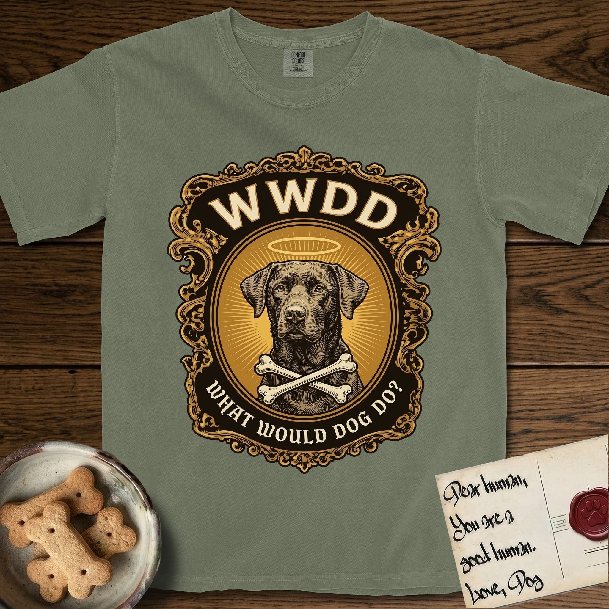 What Would Dog Do Chocolate Lab T-Shirt flat lay in Sage, featuring a baroque gold ornate portrait medallion of a haloed Chocolate Lab with the question What Would Dog Do.