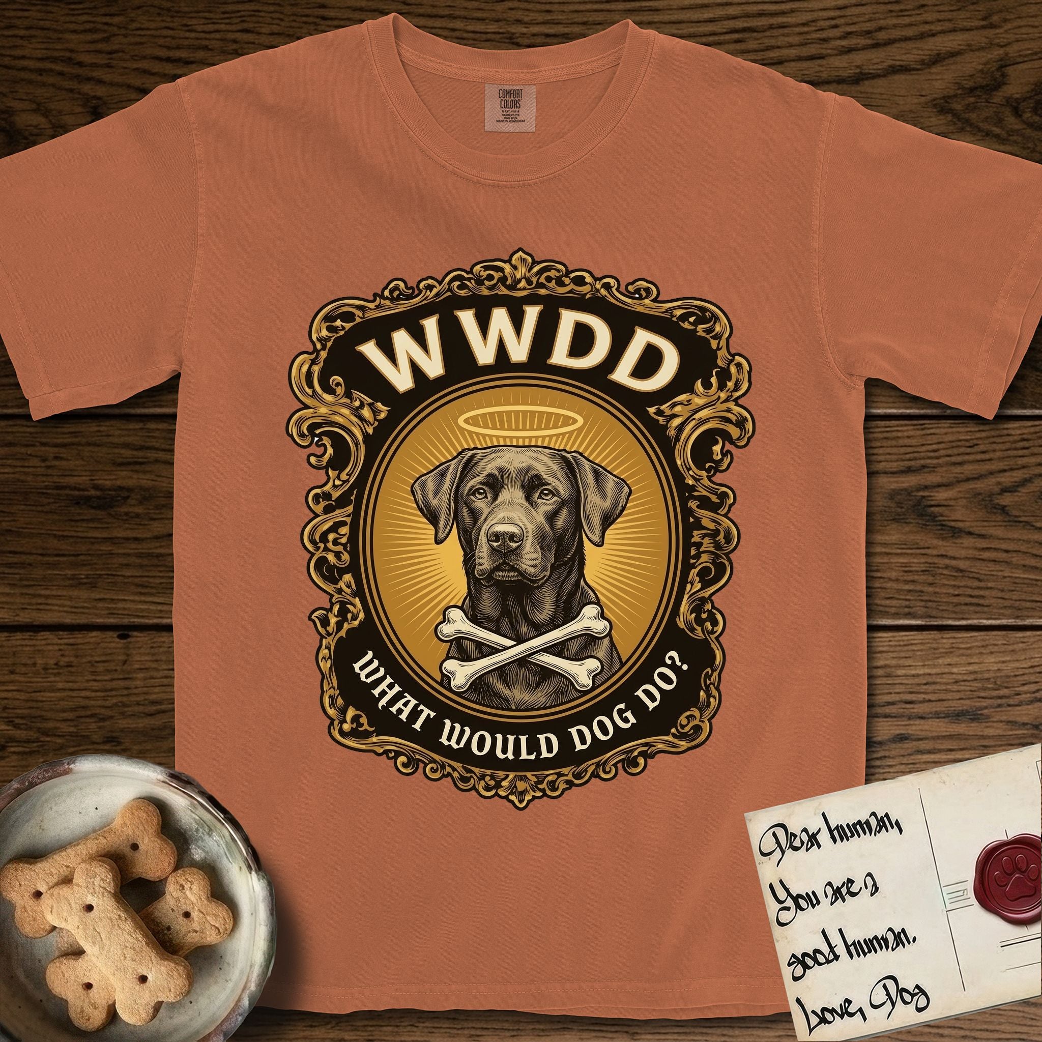 What Would Dog Do Chocolate Lab T-Shirt flat lay in Yam, featuring a baroque gold ornate portrait medallion of a haloed Chocolate Lab with the question What Would Dog Do.