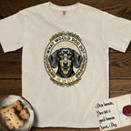 What Would Dog Do Dachshund T-Shirt flat lay in Ivory, featuring an oak-leaf and acorn framed gold portrait medallion of a haloed Dachshund with the question What Would Dog Do.