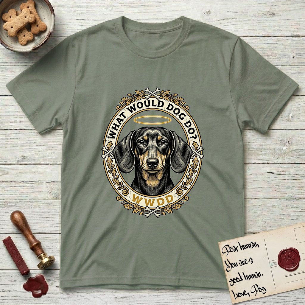 What Would Dog Do Dachshund T-Shirt flat lay in Sage, featuring an oak-leaf and acorn framed gold portrait medallion of a haloed Dachshund with the question What Would Dog Do.