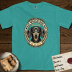 What Would Dog Do Dachshund T-Shirt flat lay in Seafoam, featuring an oak-leaf and acorn framed gold portrait medallion of a haloed Dachshund with the question What Would Dog Do.