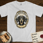 What Would Dog Do Dachshund T-Shirt flat lay in White, featuring an oak-leaf and acorn framed gold portrait medallion of a haloed Dachshund with the question What Would Dog Do.