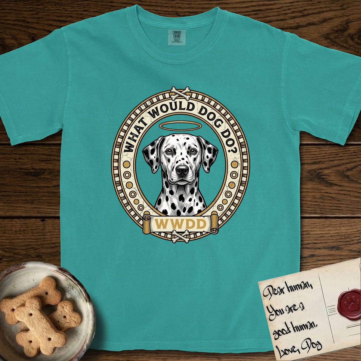 What Would Dog Do Dalmatian T-Shirt flat lay in Seafoam, featuring a vintage gold portrait medallion of a haloed Dalmatian in an engraved coin-style dotted border with the question What Would Dog Do.
