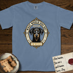 What Would Dog Do Doberman T-Shirt flat lay in Blue Jean, featuring a fleur-de-lis framed gold portrait medallion of a haloed Doberman with natural uncropped ears and the question What Would Dog Do.
