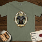 What Would Dog Do Doberman T-Shirt flat lay in Sage, featuring a fleur-de-lis framed gold portrait medallion of a haloed Doberman with natural uncropped ears and the question What Would Dog Do.