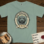 What Would Dog Do Goldendoodle T-Shirt flat lay in Bay, featuring an ornate scrollwork gold portrait medallion of a haloed Goldendoodle with the question What Would Dog Do.