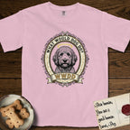 What Would Dog Do Goldendoodle T-Shirt flat lay in Blossom, featuring an ornate scrollwork gold portrait medallion of a haloed Goldendoodle with the question What Would Dog Do.