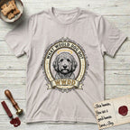 What Would Dog Do Goldendoodle T-Shirt flat lay in Ice Grey, featuring an ornate scrollwork gold portrait medallion of a haloed Goldendoodle with the question What Would Dog Do.