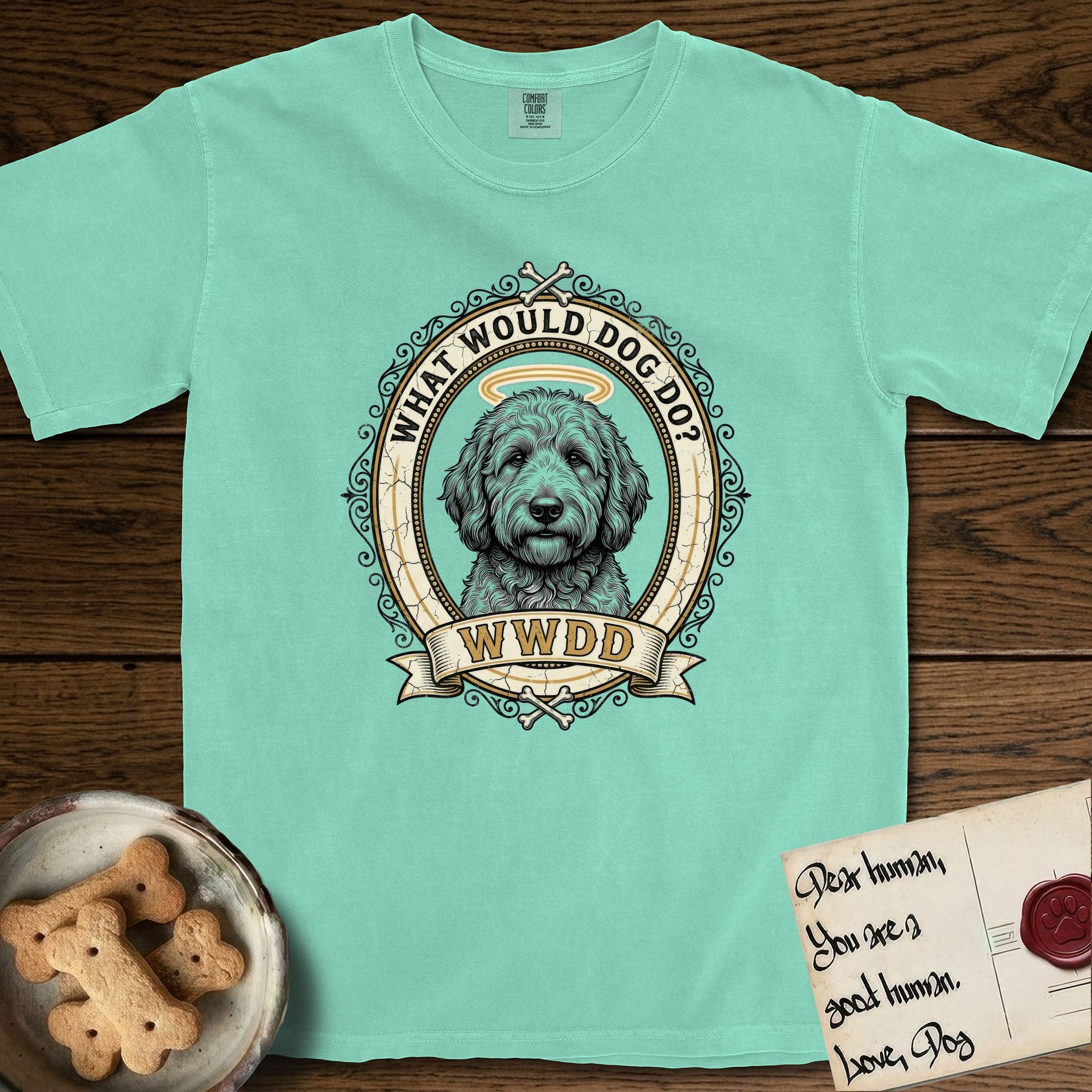 What Would Dog Do Goldendoodle T-Shirt flat lay in Island Reef, featuring an ornate scrollwork gold portrait medallion of a haloed Goldendoodle with the question What Would Dog Do.