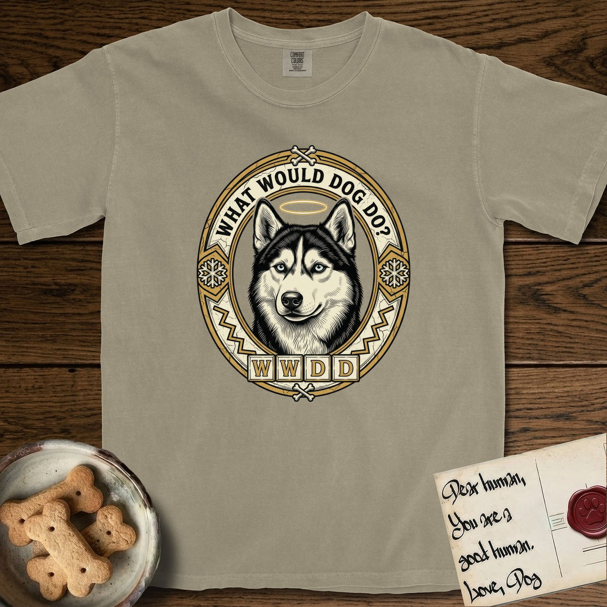 What Would Dog Do Husky T-Shirt flat lay in Khaki, featuring a vintage gold portrait medallion of a haloed blue-eyed Husky in a Nordic snowflake border with the question What Would Dog Do.