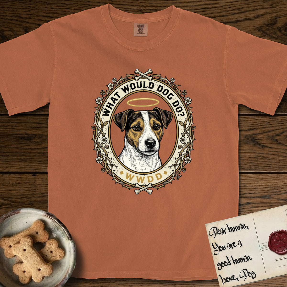 What Would Dog Do Jack Russell T-Shirt flat lay in Yam, featuring a vintage gold portrait medallion of a haloed Jack Russell in a wreath of thorned branches and wildflowers with the question What Would Dog Do.