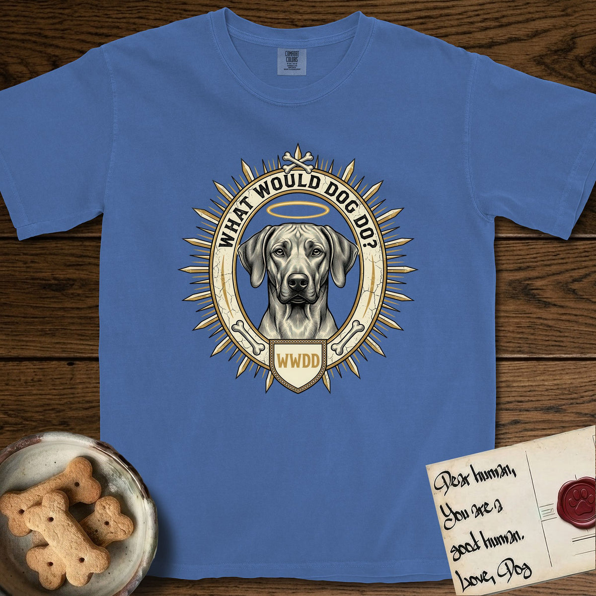 What Would Dog Do Rhodesian Ridgeback T-Shirt flat lay in Mystic Blue, featuring a vintage gold portrait medallion of a haloed Rhodesian Ridgeback ringed by radiating sunburst spikes with the question What Would Dog Do.