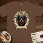 What Would Dog Do Rottweiler T-Shirt flat lay in Espresso, featuring a vintage gold portrait medallion of a haloed Rottweiler framed by studded leather collar straps and buckles with the question What Would Dog Do.