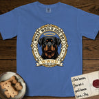 What Would Dog Do Rottweiler T-Shirt flat lay in Mystic Blue, featuring a vintage gold portrait medallion of a haloed Rottweiler framed by studded leather collar straps and buckles with the question What Would Dog Do.