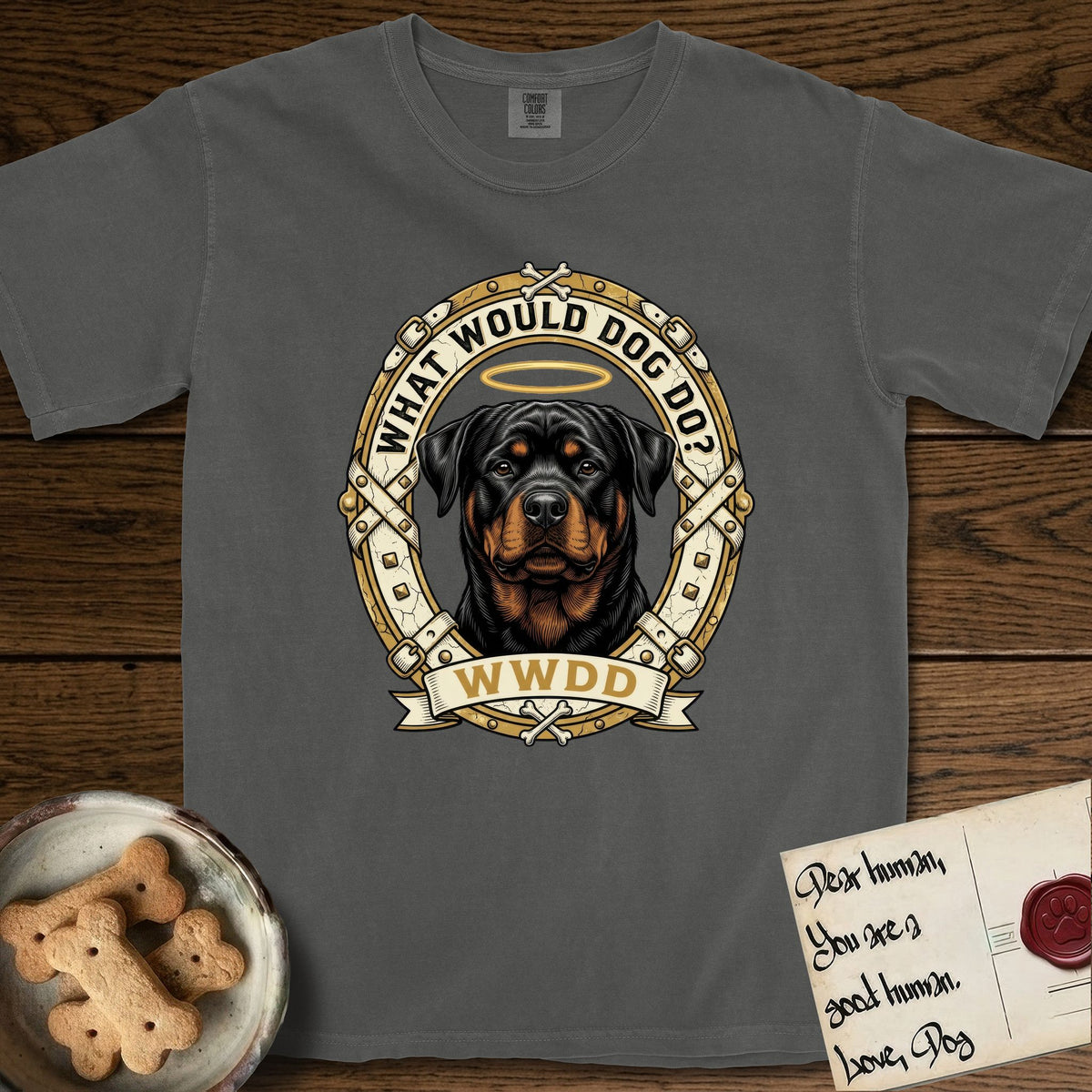 What Would Dog Do Rottweiler T-Shirt flat lay in Pepper, featuring a vintage gold portrait medallion of a haloed Rottweiler framed by studded leather collar straps and buckles with the question What Would Dog Do.