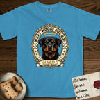 What Would Dog Do Rottweiler T-Shirt flat lay in Royal Caribe, featuring a vintage gold portrait medallion of a haloed Rottweiler framed by studded leather collar straps and buckles with the question What Would Dog Do.