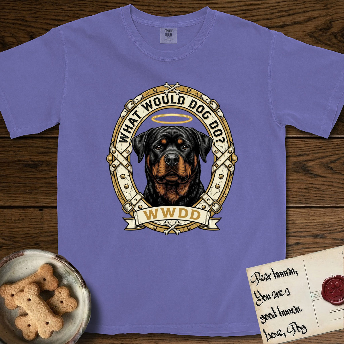What Would Dog Do Rottweiler T-Shirt flat lay in Violet, featuring a vintage gold portrait medallion of a haloed Rottweiler framed by studded leather collar straps and buckles with the question What Would Dog Do.