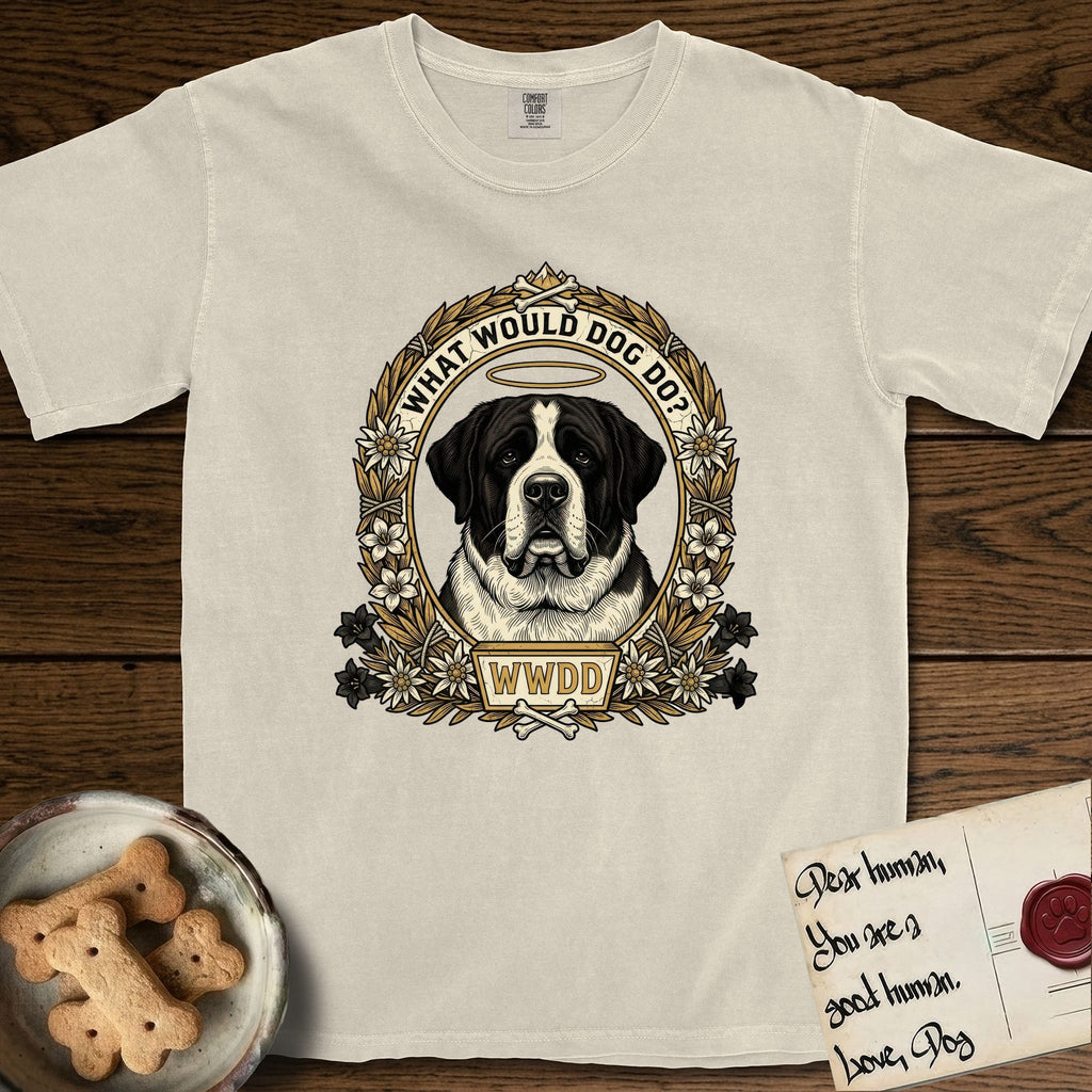 What Would Dog Do Saint Bernard T-Shirt flat lay in Ivory, featuring a vintage gold portrait medallion of a haloed Saint Bernard in an alpine laurel wreath with edelweiss blossoms and the question What Would Dog Do.