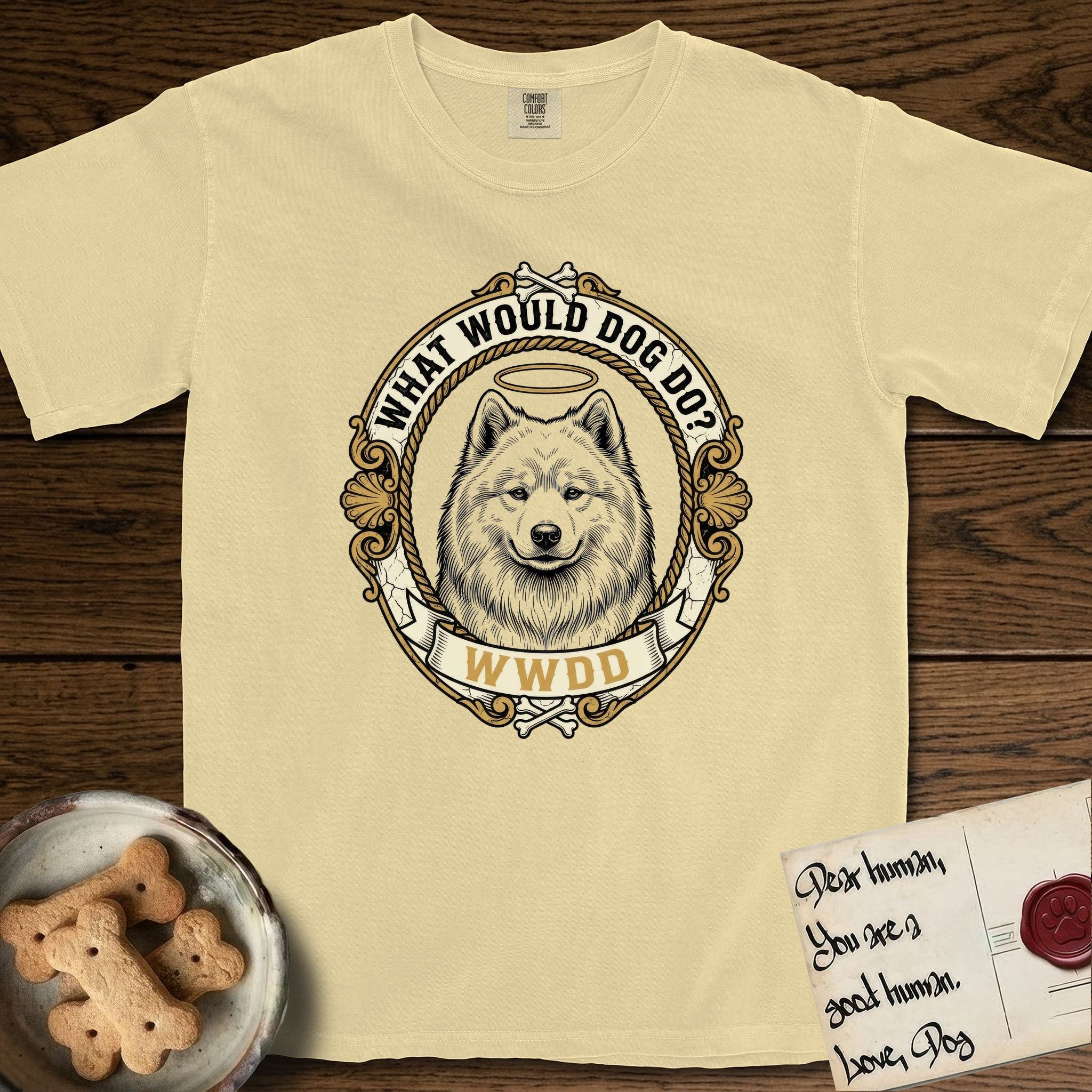 What Would Dog Do Samoyed T-Shirt flat lay in Butter, featuring a rope-twist framed gold portrait medallion of a haloed Samoyed with the question What Would Dog Do.