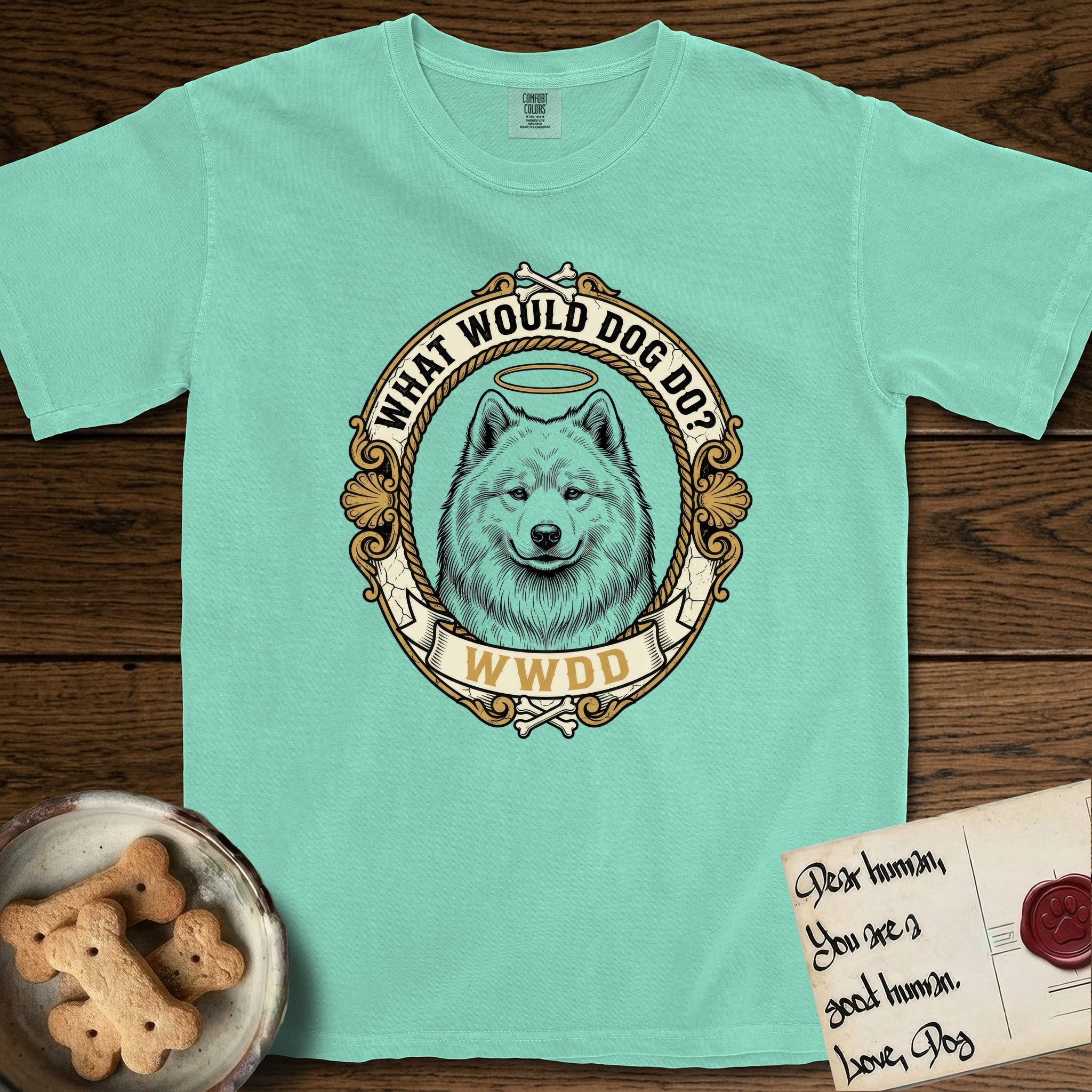 What Would Dog Do Samoyed T-Shirt flat lay in Island Reef, featuring a rope-twist framed gold portrait medallion of a haloed Samoyed with the question What Would Dog Do.
