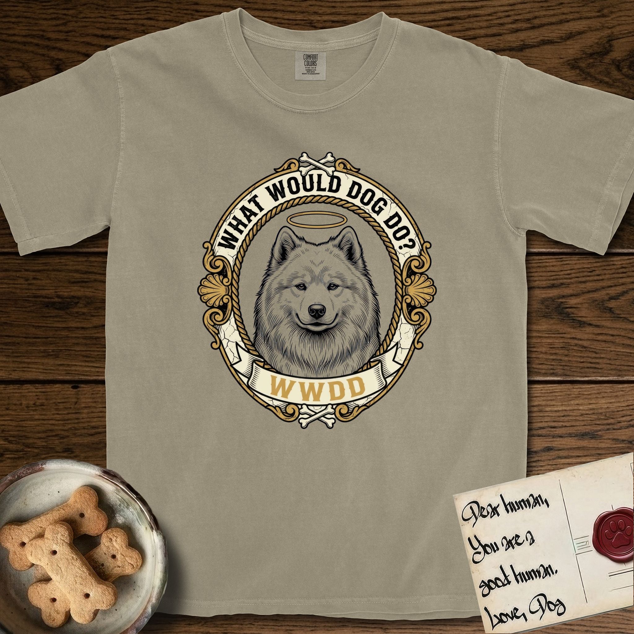 What Would Dog Do Samoyed T-Shirt flat lay in Khaki, featuring a rope-twist framed gold portrait medallion of a haloed Samoyed with the question What Would Dog Do.