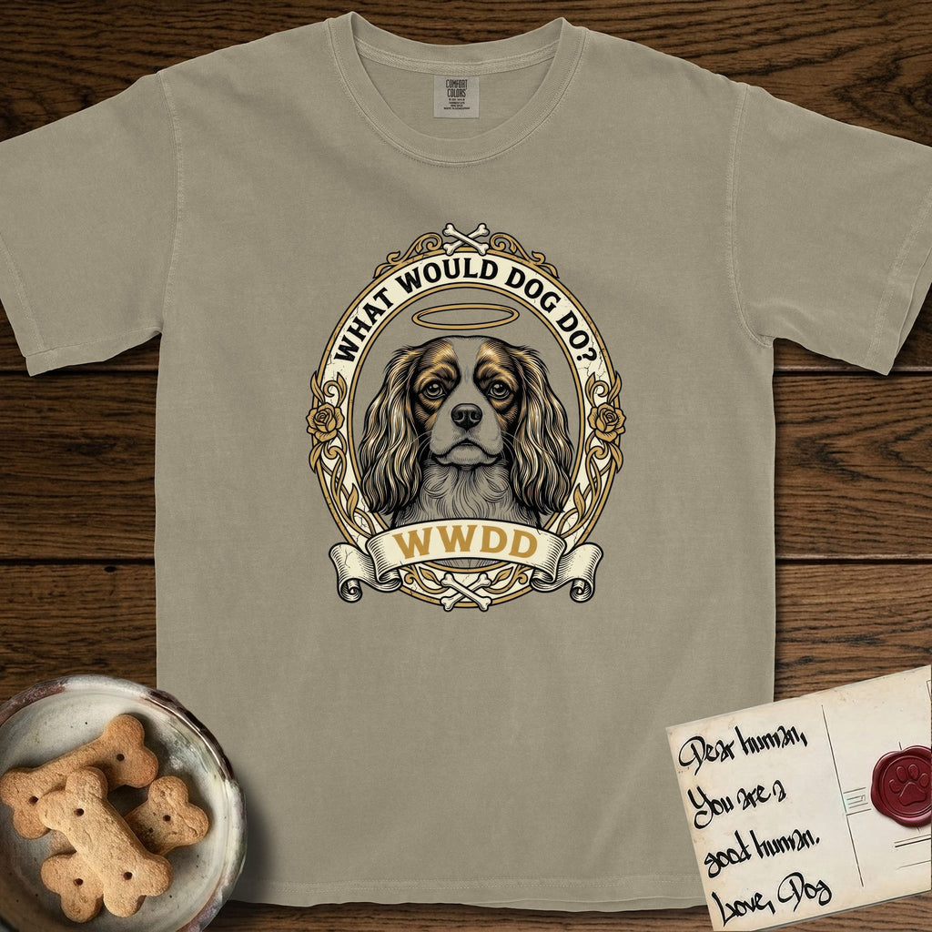 What Would Dog Do Cavalier T-Shirt flat lay in Khaki, featuring a rose-bordered gold portrait medallion of a haloed Cavalier King Charles Spaniel with the question What Would Dog Do.