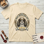 What Would Dog Do Spaniel T-Shirt flat lay in Natural, featuring a rose-bordered gold portrait medallion of a haloed Cavalier King Charles Spaniel with the question What Would Dog Do.