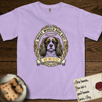 What Would Dog Do Cavalier T-Shirt flat lay in Orchid, featuring a rose-bordered gold portrait medallion of a haloed Cavalier King Charles Spaniel with the question What Would Dog Do.