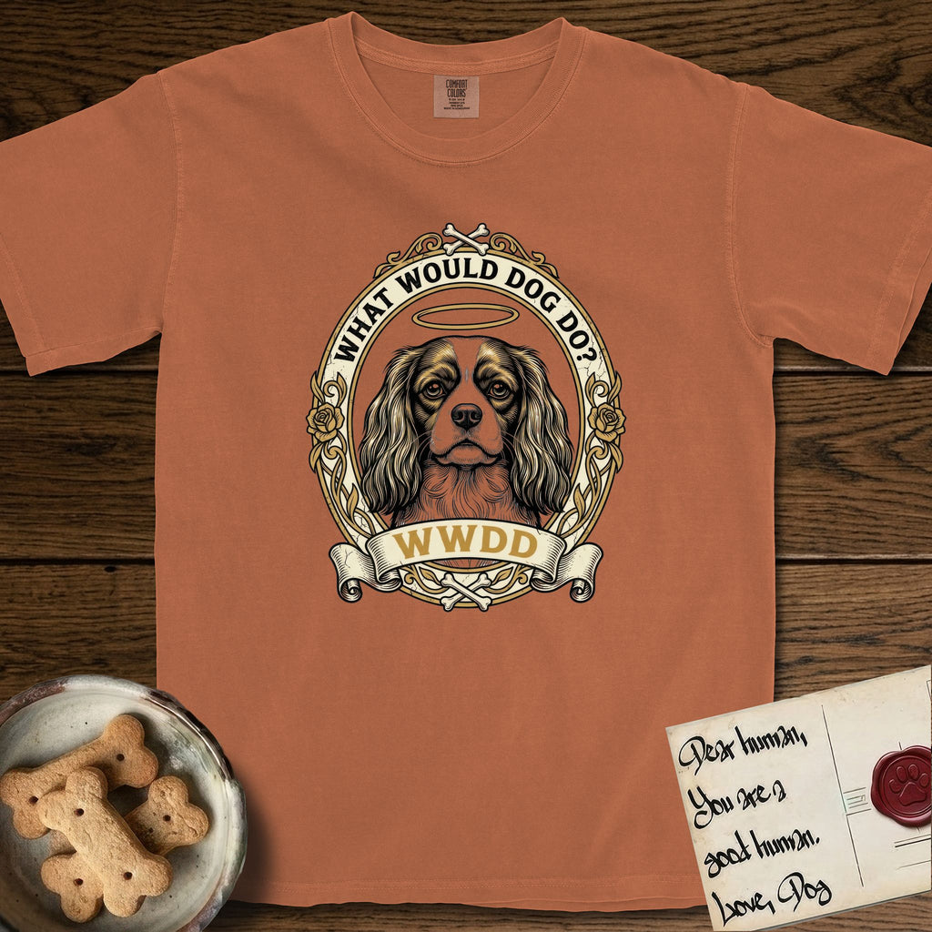 What Would Dog Do Cavalier T-Shirt flat lay in Yam, featuring a rose-bordered gold portrait medallion of a haloed Cavalier King Charles Spaniel with the question What Would Dog Do.
