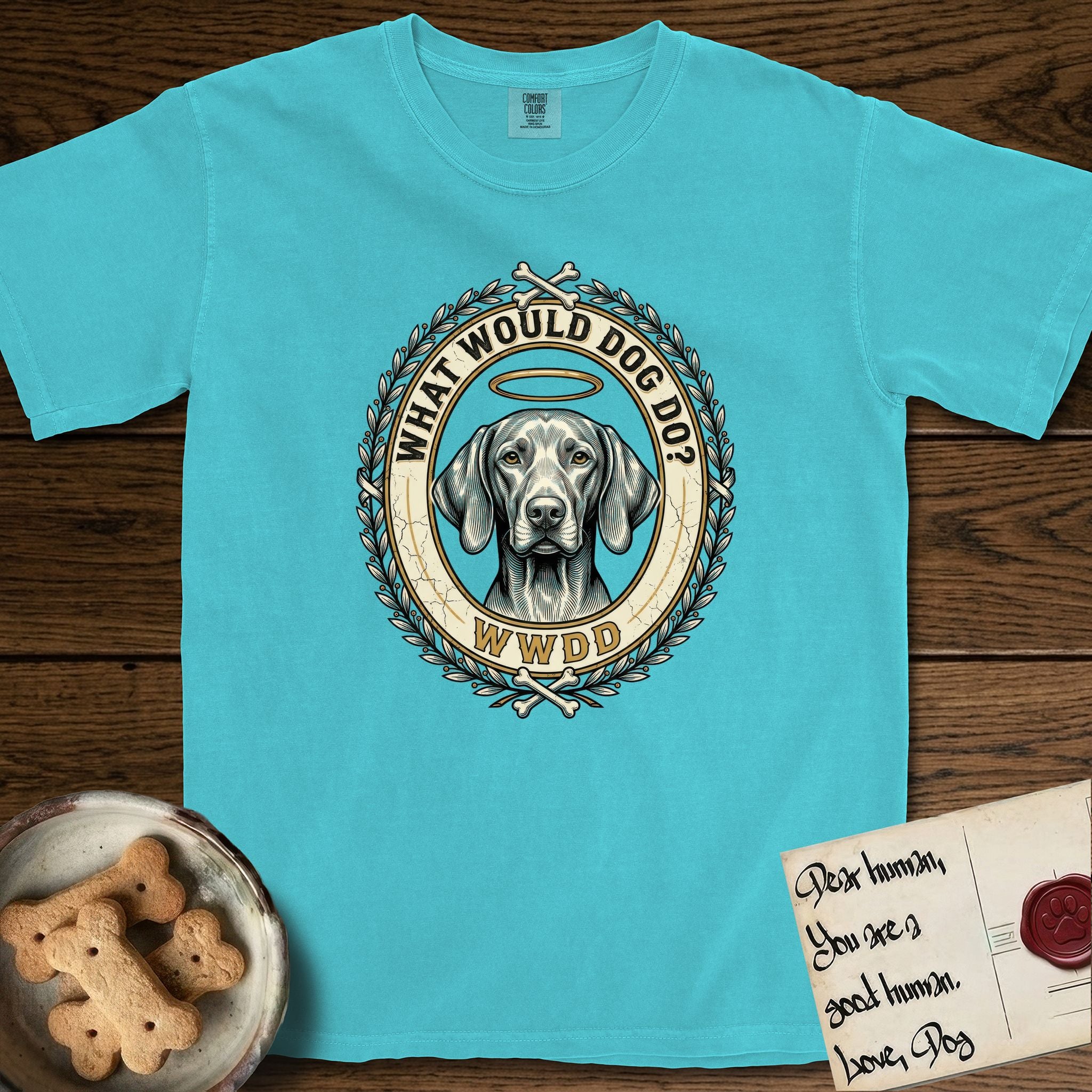 What Would Dog Do Vizsla T-Shirt flat lay in Lagoon Blue, featuring a laurel-wreath framed gold portrait medallion of a haloed Vizsla with the question What Would Dog Do.