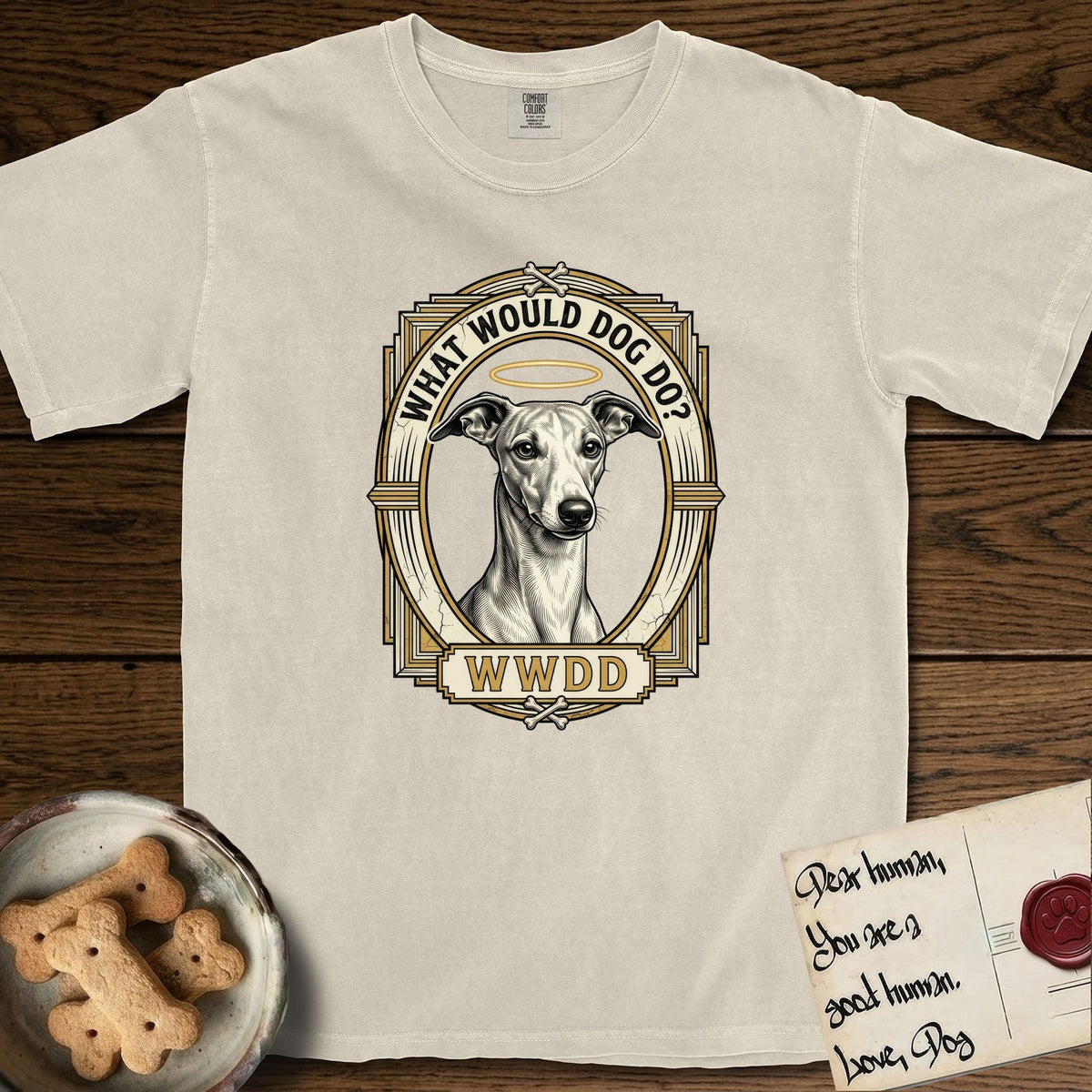 What Would Dog Do Whippet T-Shirt flat lay in Ivory, featuring a vintage gold portrait medallion of a haloed Whippet in an Art Deco stepped frame with the question What Would Dog Do.