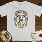 What Would Dog Do Whippet T-Shirt flat lay in White, featuring a vintage gold portrait medallion of a haloed Whippet in an Art Deco stepped frame with the question What Would Dog Do.